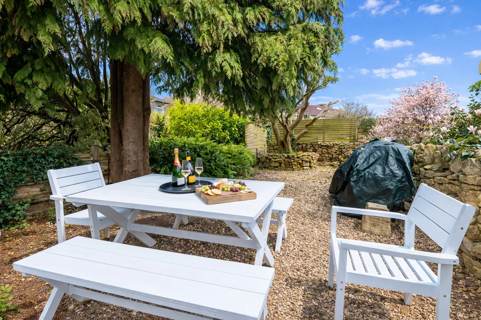 White garden table and benches under the trees in the communal garden